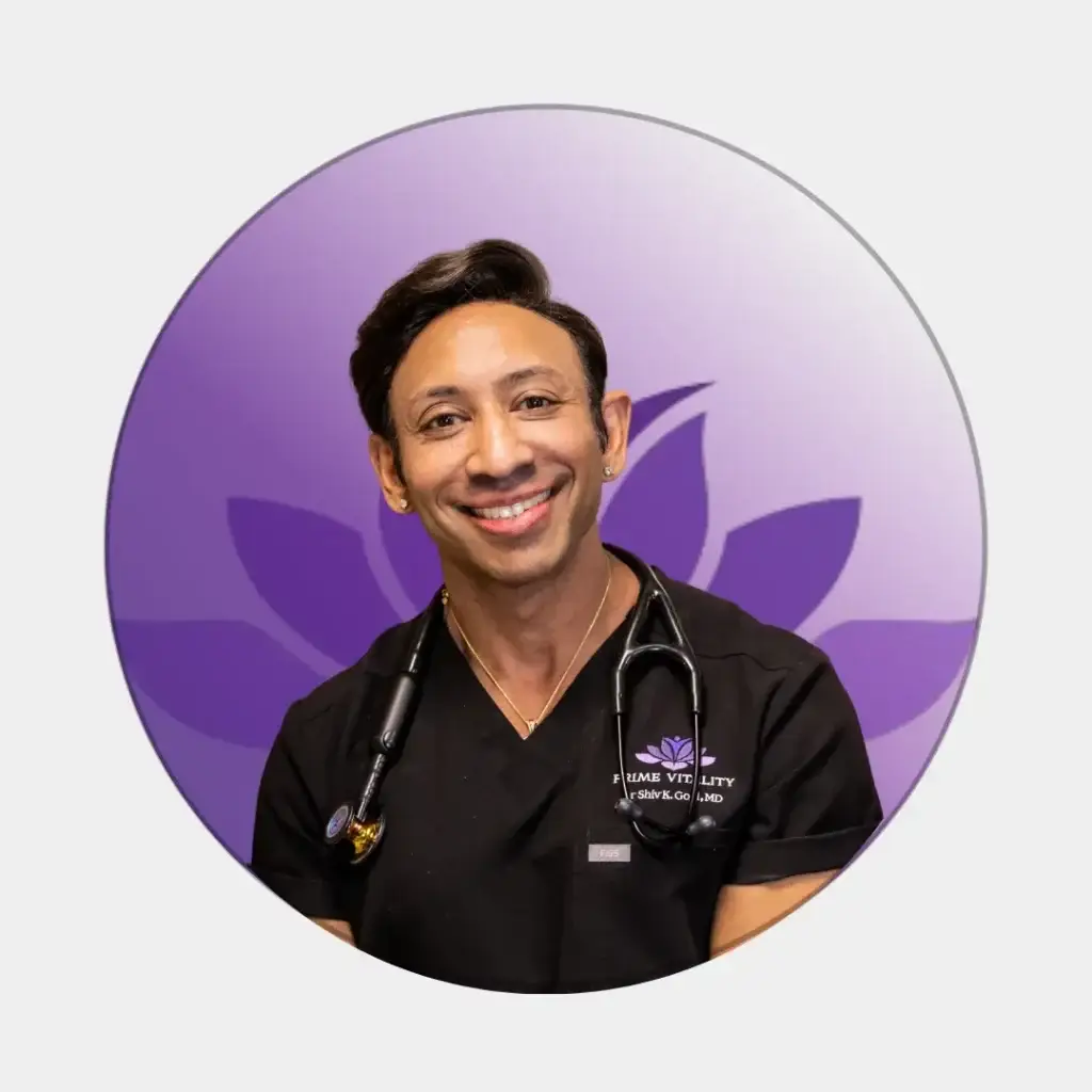 Smiling male doctor in black scrubs with stethoscope, purple background.